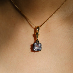 gold chain necklace with a square-cut clear gemstone pendant.