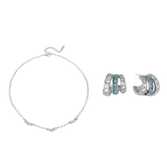 A jewelry set featuring a delicate silver chain bracelet and matching silver huggie hoop earrings, both adorned with small light blue stones, displayed on a clean white background.