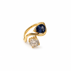 A gold ring featuring a pear-cut blue gemstone and a round clear gemstone. 